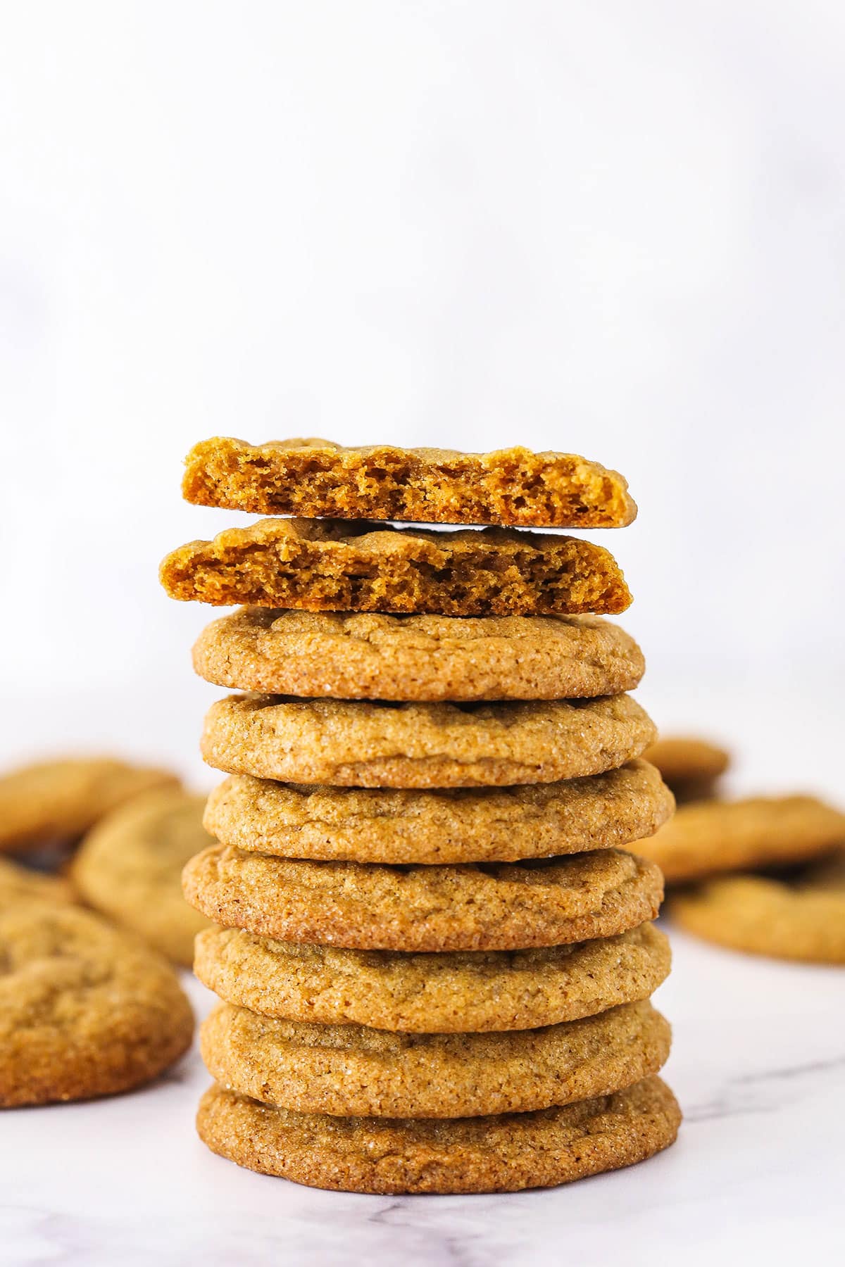 A tall stack of molasses cookies with the top one cut in half.