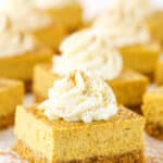 Pumpkin Cheesecake Bars topped with frosting swirls on a white table