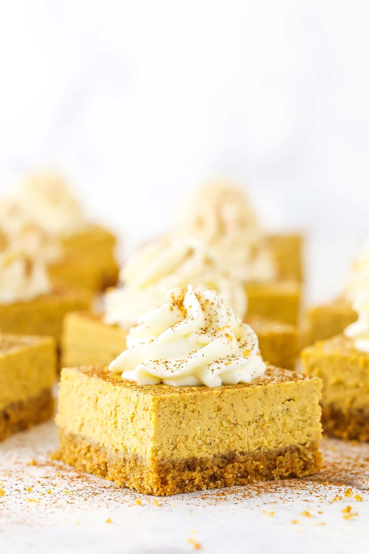 Pumpkin Cheesecake Bars topped with frosting swirls on a white table