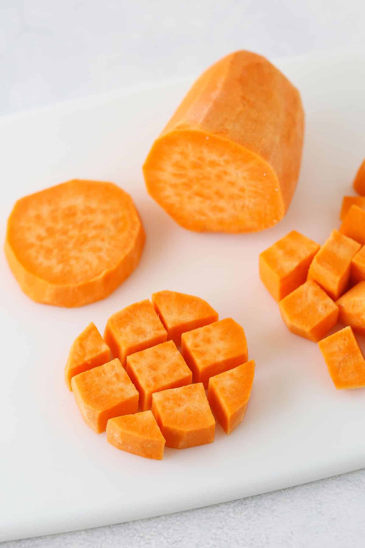 Half-inch cubes of a peeled sweet potato on a cutting board.