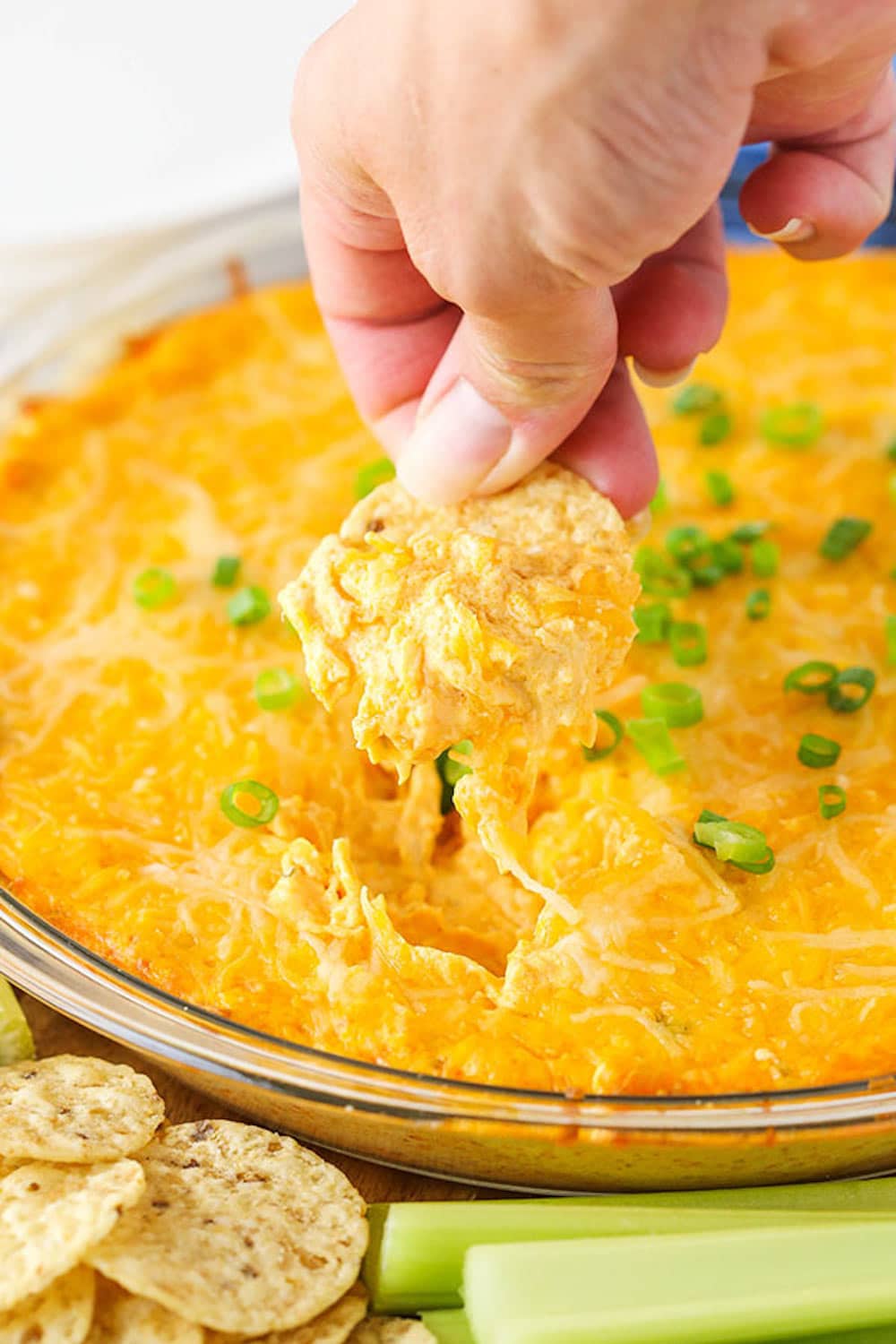 A Chip Scooping up some Cheesy Buffalo Dip from a Clear Bowl