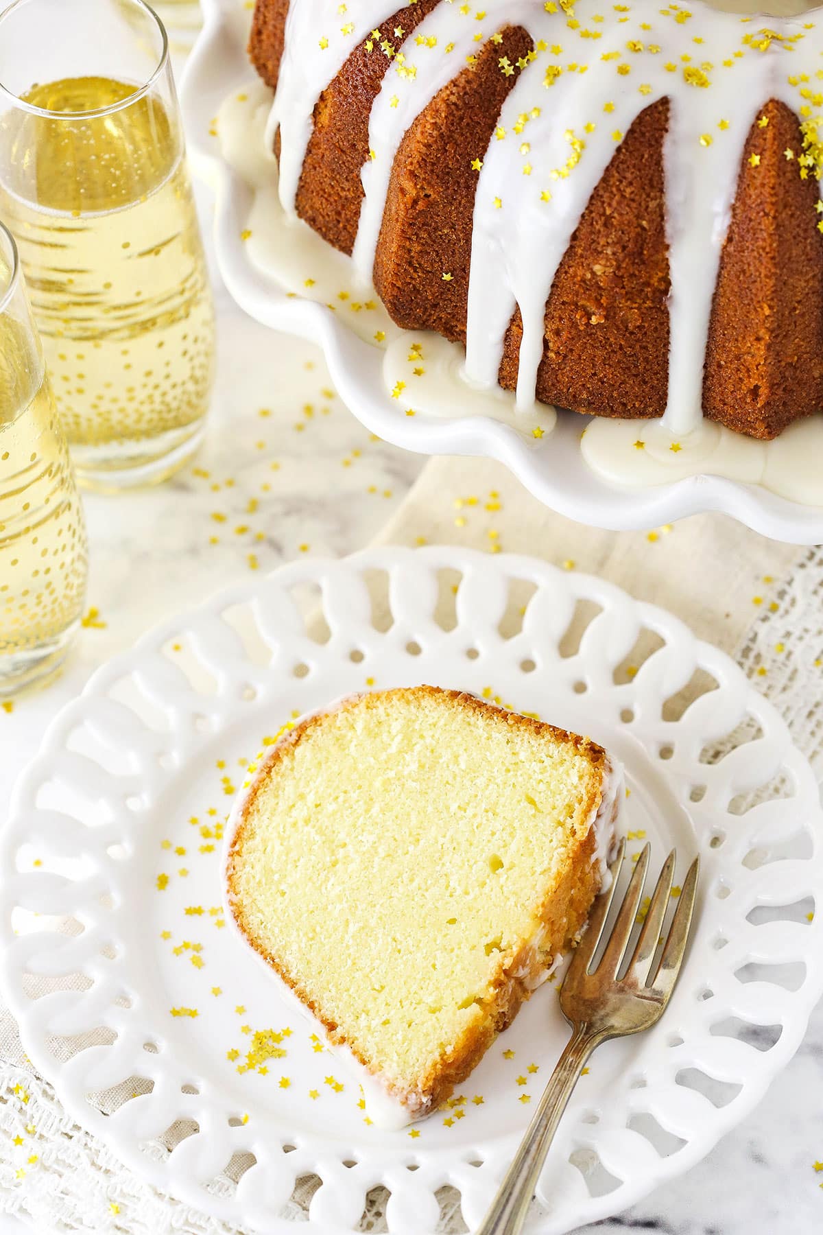 A Slice of Pound Cake on a Plate Next to Two Glasses of Champagne.