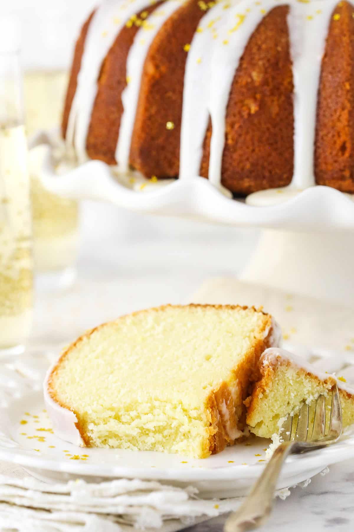 A Piece of Champagne Cake on a White Plate with One Bite on a Fork.