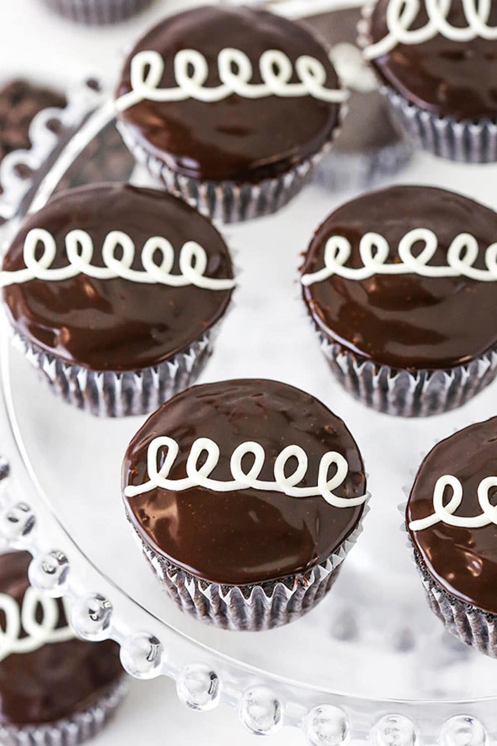 Six Homemade Hostess Cupcakes on a Decorative Glass Cake Stand.