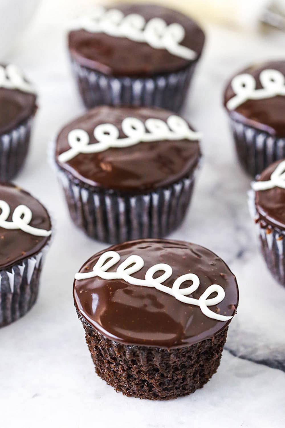 Homemade Hostess Cupcakes Lined up on a Black and White Marble Surface.