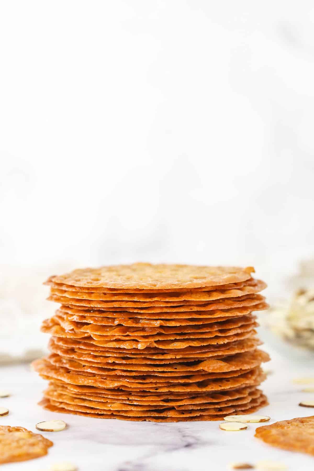 Lace Cookies Stacked on a White Counter with Almond Shavings