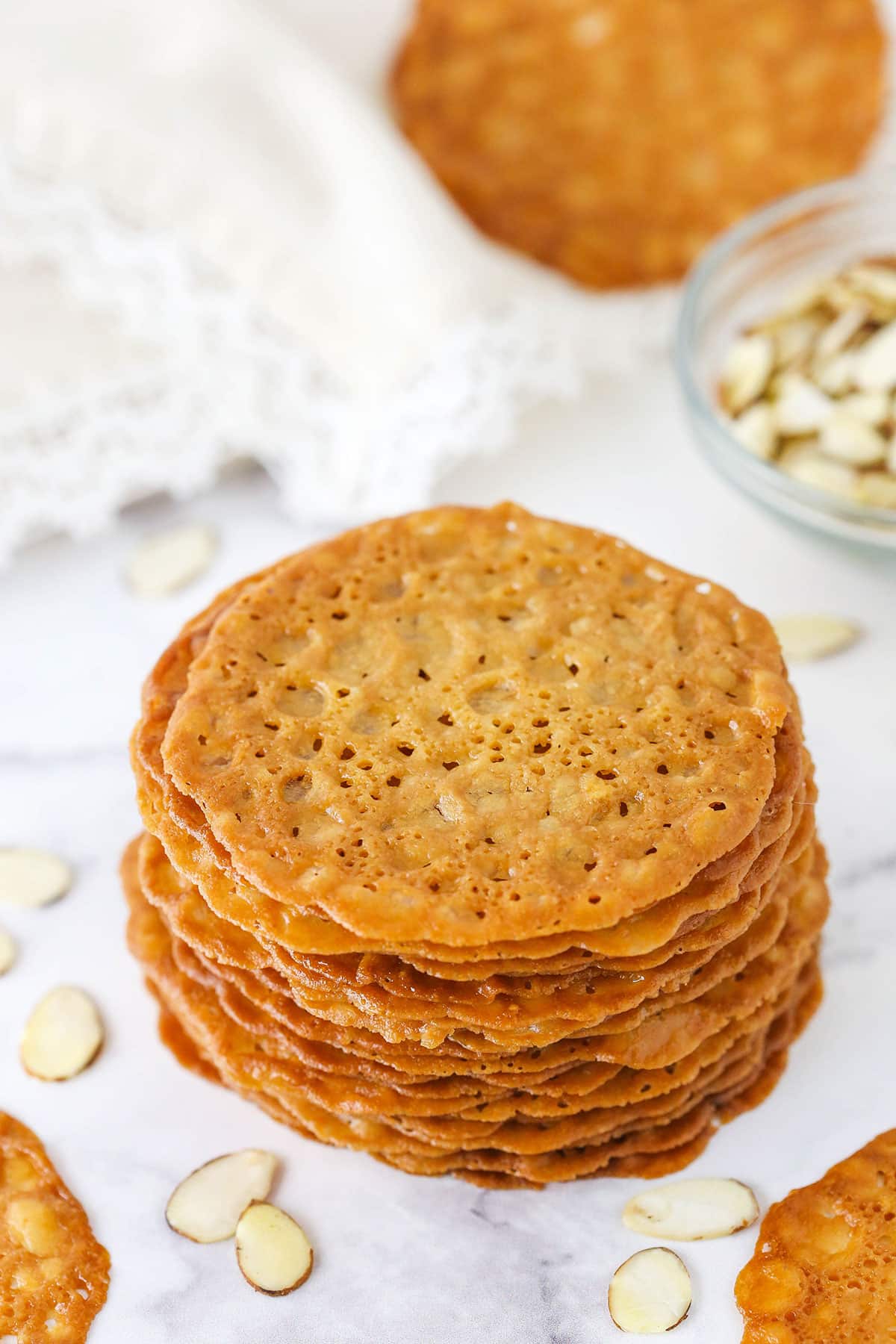 Lace Cookies Beside a Glass Bowl of Sliced Almonds