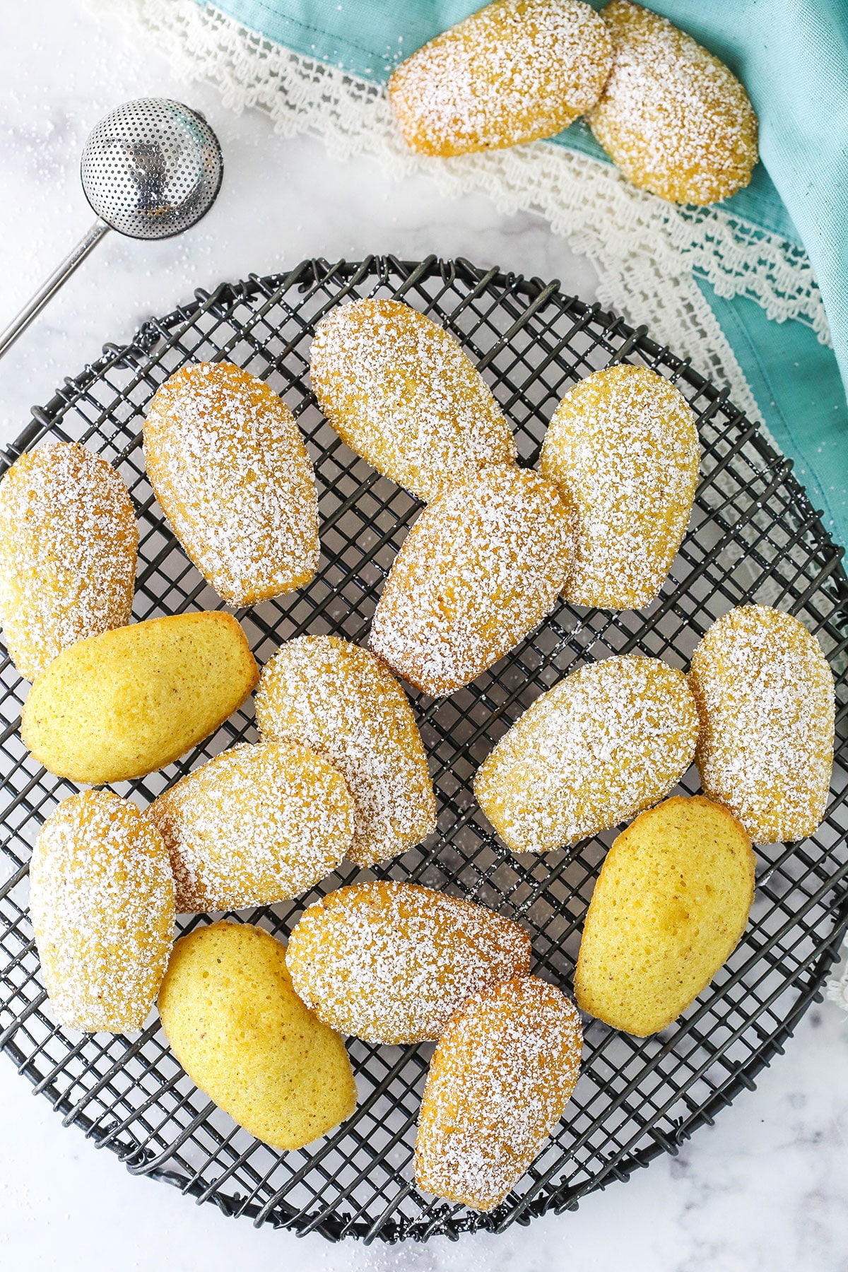 Madeleines dusted with powdered sugar on a cooling rack.