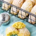 A Madeleine Tea Cake Broken in Half on a Teal Napkin with Other Cookies Nearby.