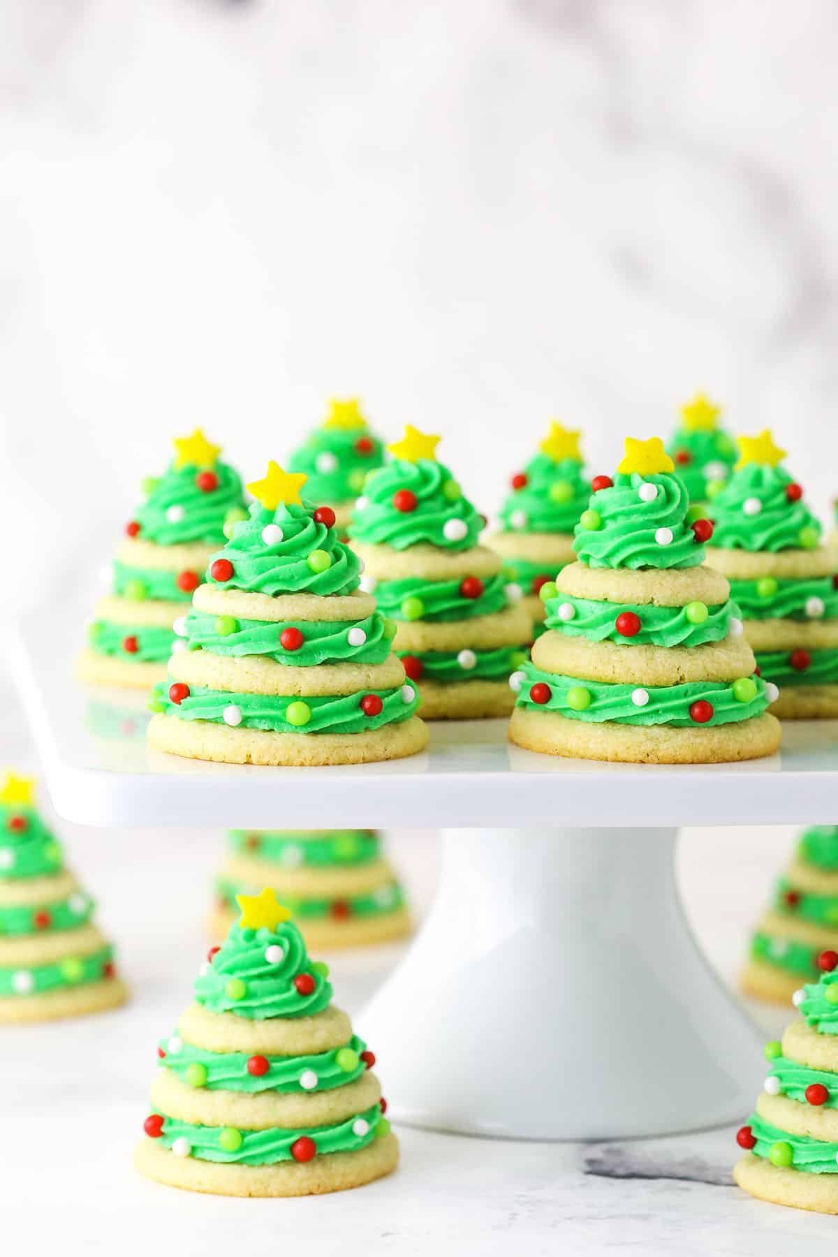 Sugar cookie Christmas trees on white cake stand.