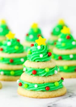 Stacked sugar cookie Christmas trees on marble table.