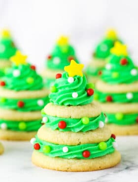 Stacked sugar cookie Christmas trees on marble table.