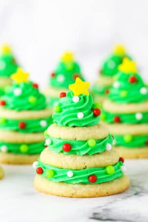 Stacked sugar cookie Christmas trees on marble table.