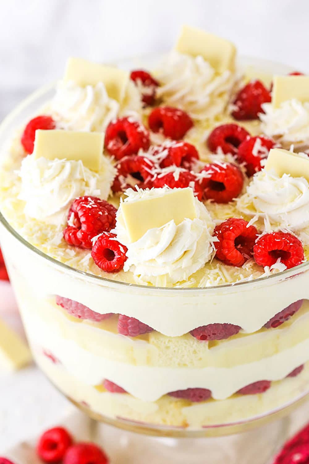 White chocolate raspberry trifle topped with swirls of whipped cream, fresh raspberries, and chocolate shavings.