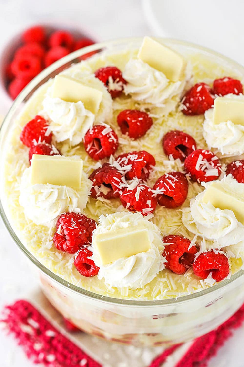 A White Chocolate Raspberry Trifle Next to a Bowl of Raspberries, Seen from Above.