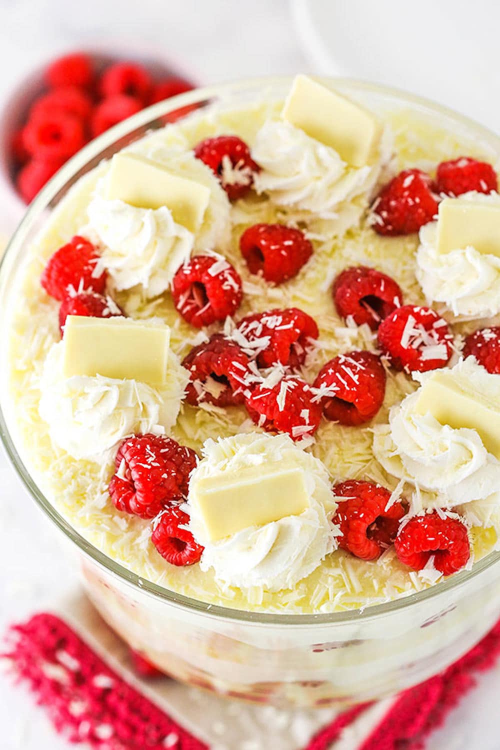 White chocolate raspberry trifle topped with swirls of whipped cream, fresh raspberries, and chocolate shavings.