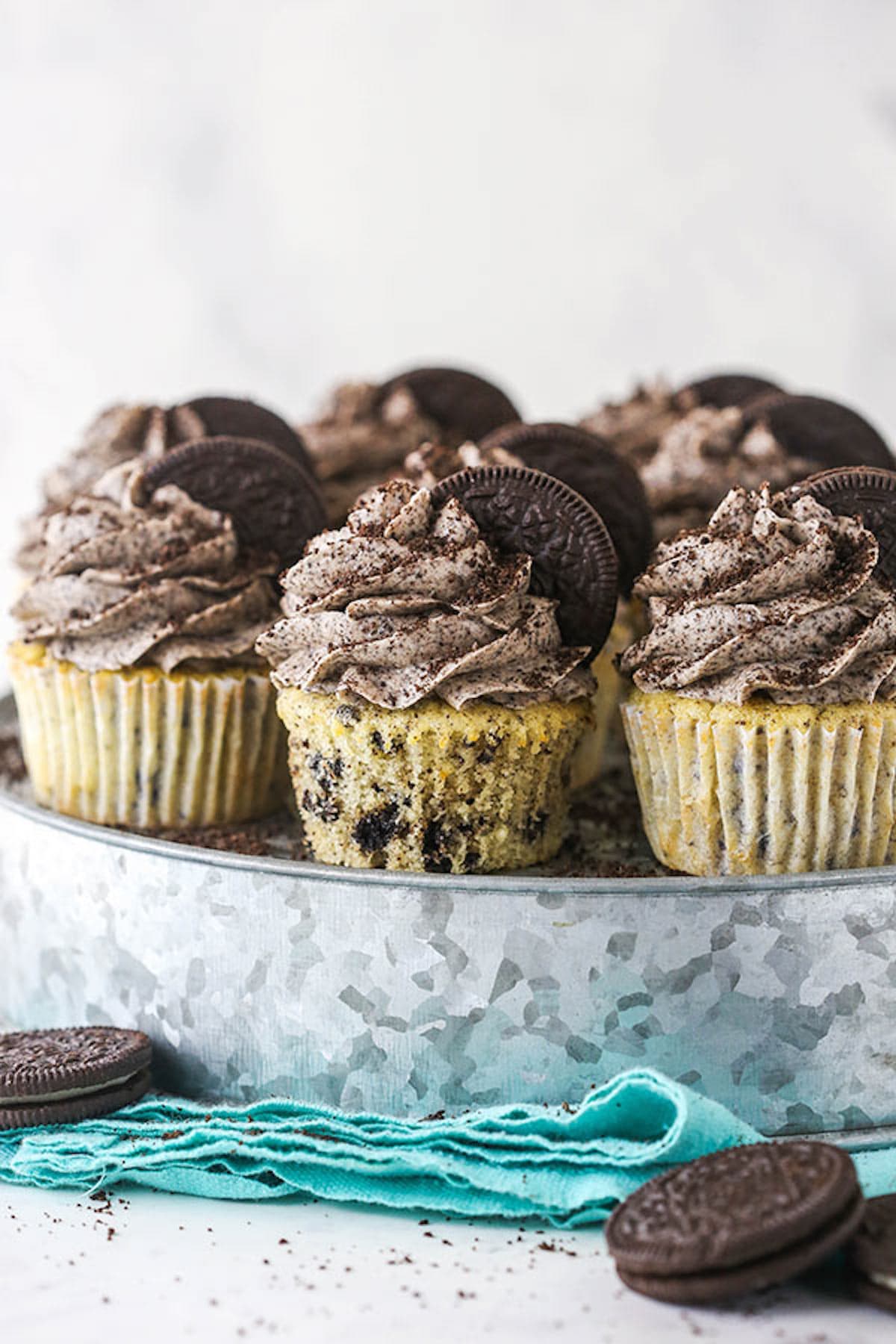 Side view of frosted Oreo Cupcakes with Oreos on top and arranged on a metal cake stand. 