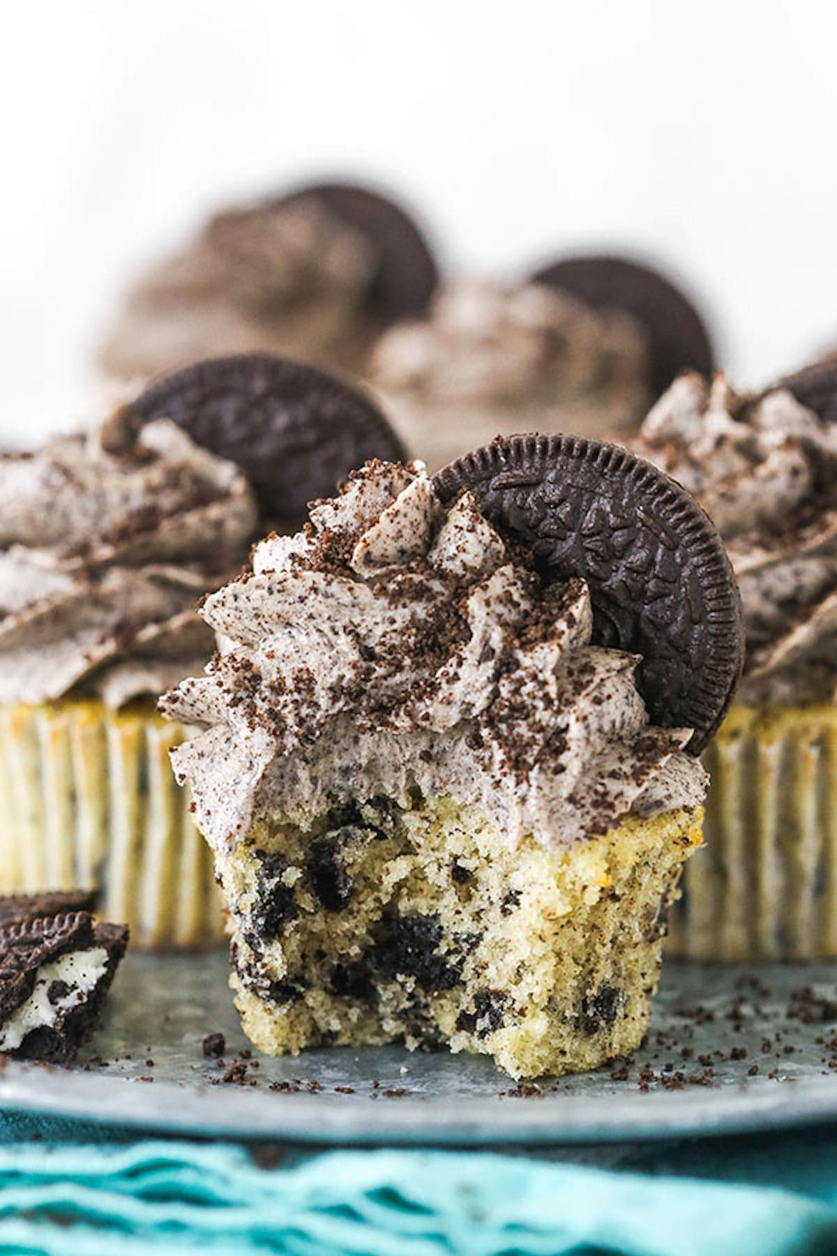 Side view of an Oreo Cupcake on a serving platter with a bite taken out of it.