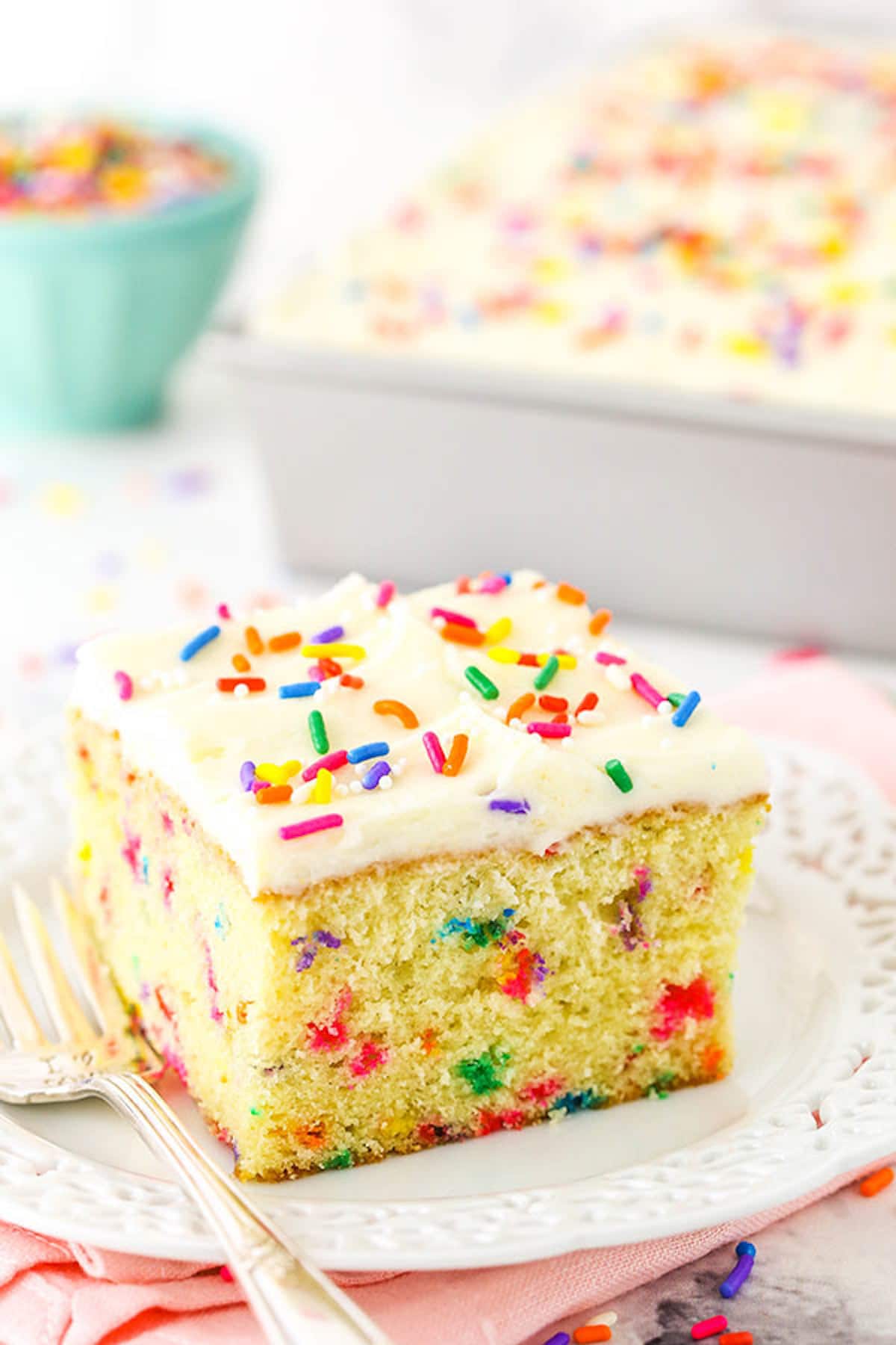 A slice of Funfetti Cake on a plate with a lace-patterned border.