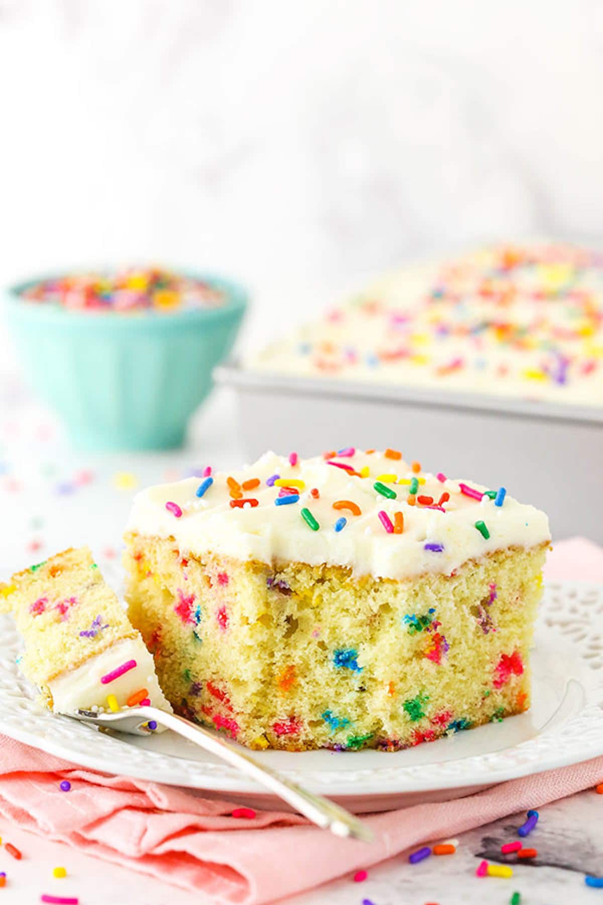 A square slice of Funfetti Cake with one bite on a fork.