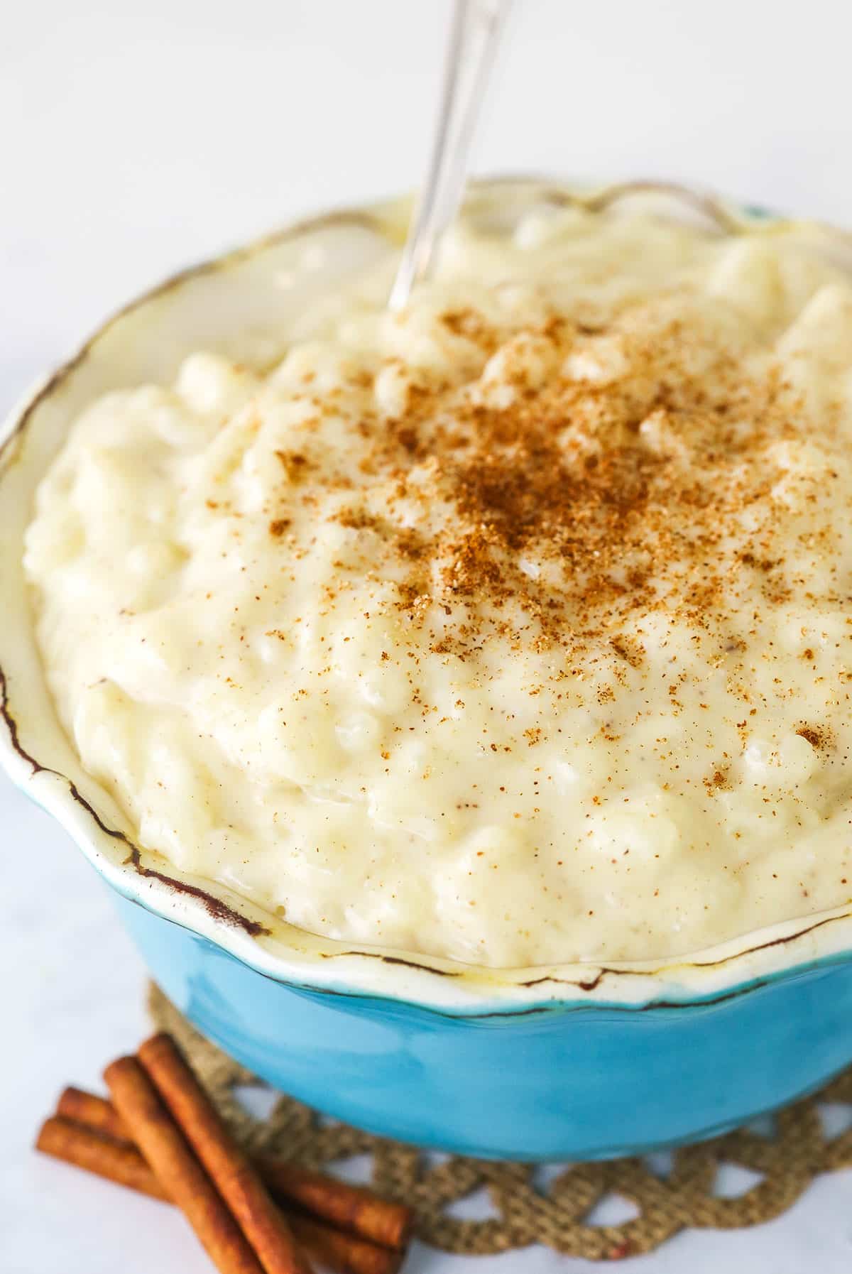 A Teal Bowl full of Creamy Rice Pudding Topped with Ground Cinnamon.