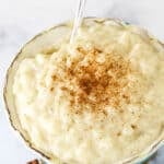 Warm Rice Pudding in a Teal Bowl with a Silver Spoon.