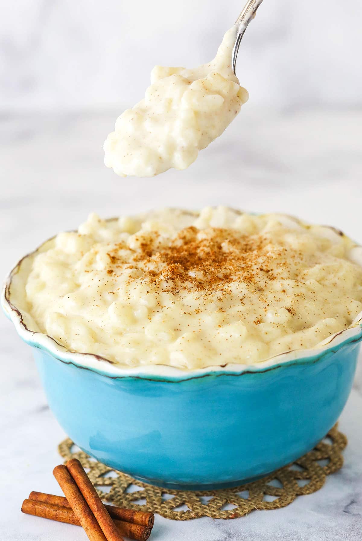 A Spoonful of Rice Pudding Hovering Over a Full Bowl.