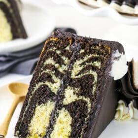 A Piece of Zebra Cake on a Plate with a Wooden Spoon