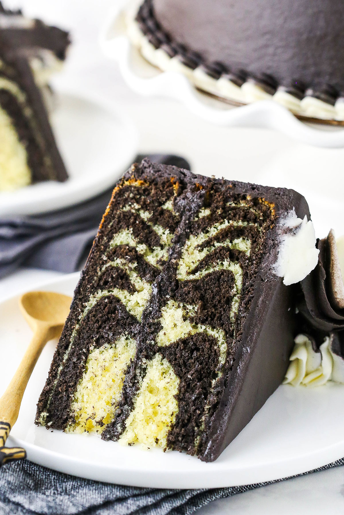 A piece of Zebra Cake on a plate with a wooden spoon.