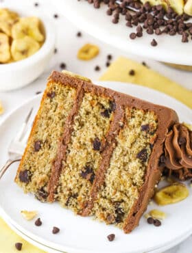 slice of banana chocolate chip cake on white plate with yellow napkin