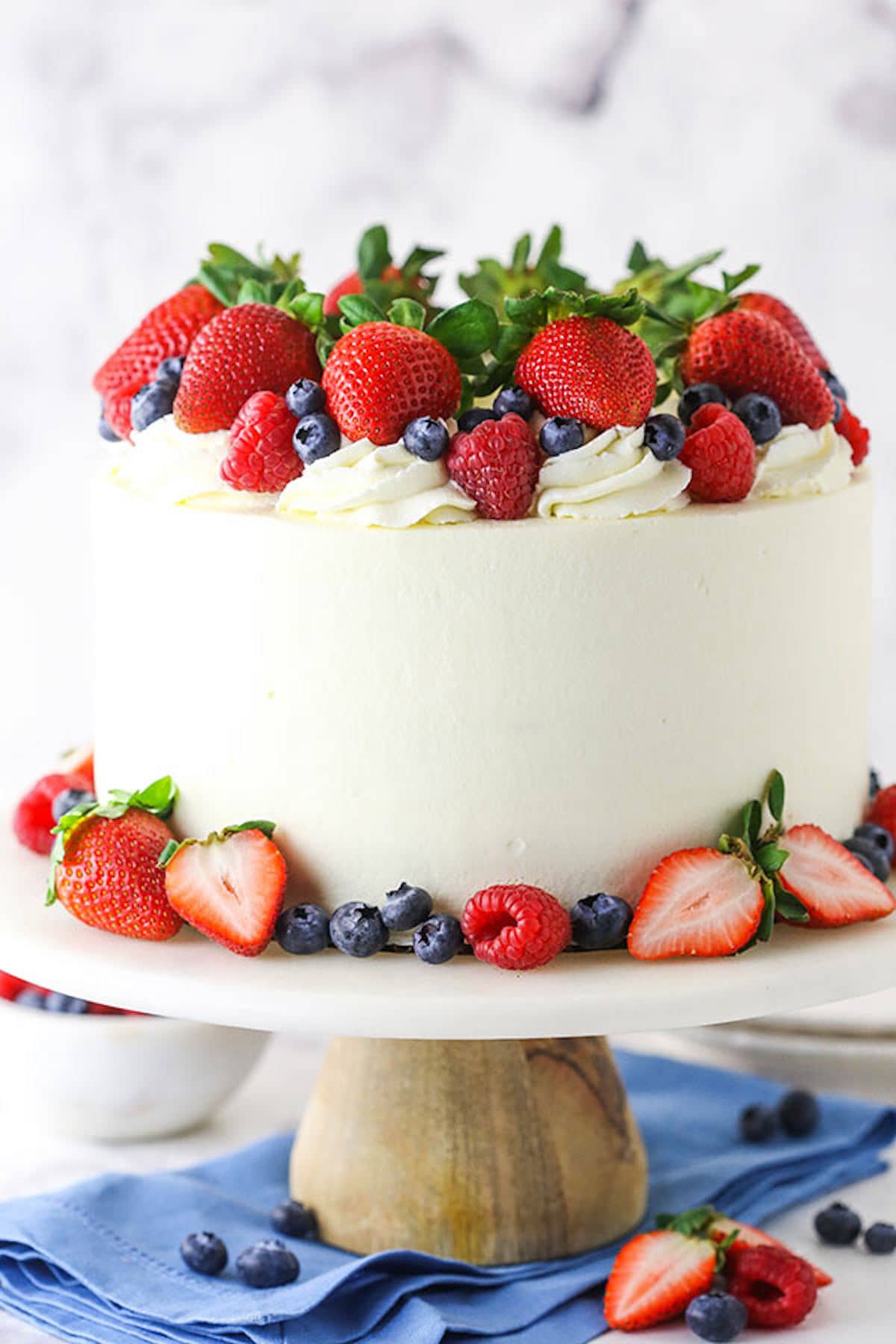 A Decorated Berry Layer Cake with Chantilly Cream Frosting on a Cake Stand