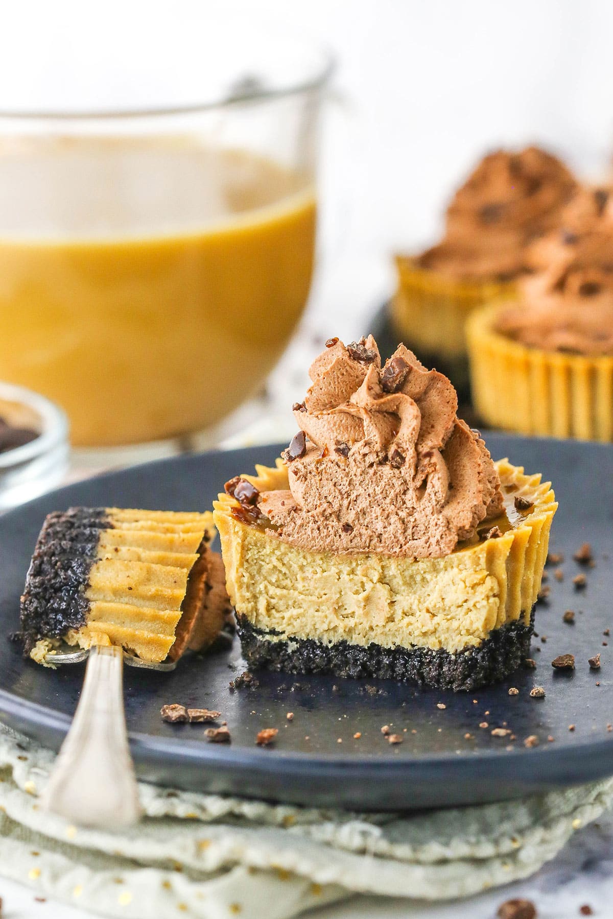 A coffee cheesecake cup cut in half showing the interior of the crust and cheesecake filling. 