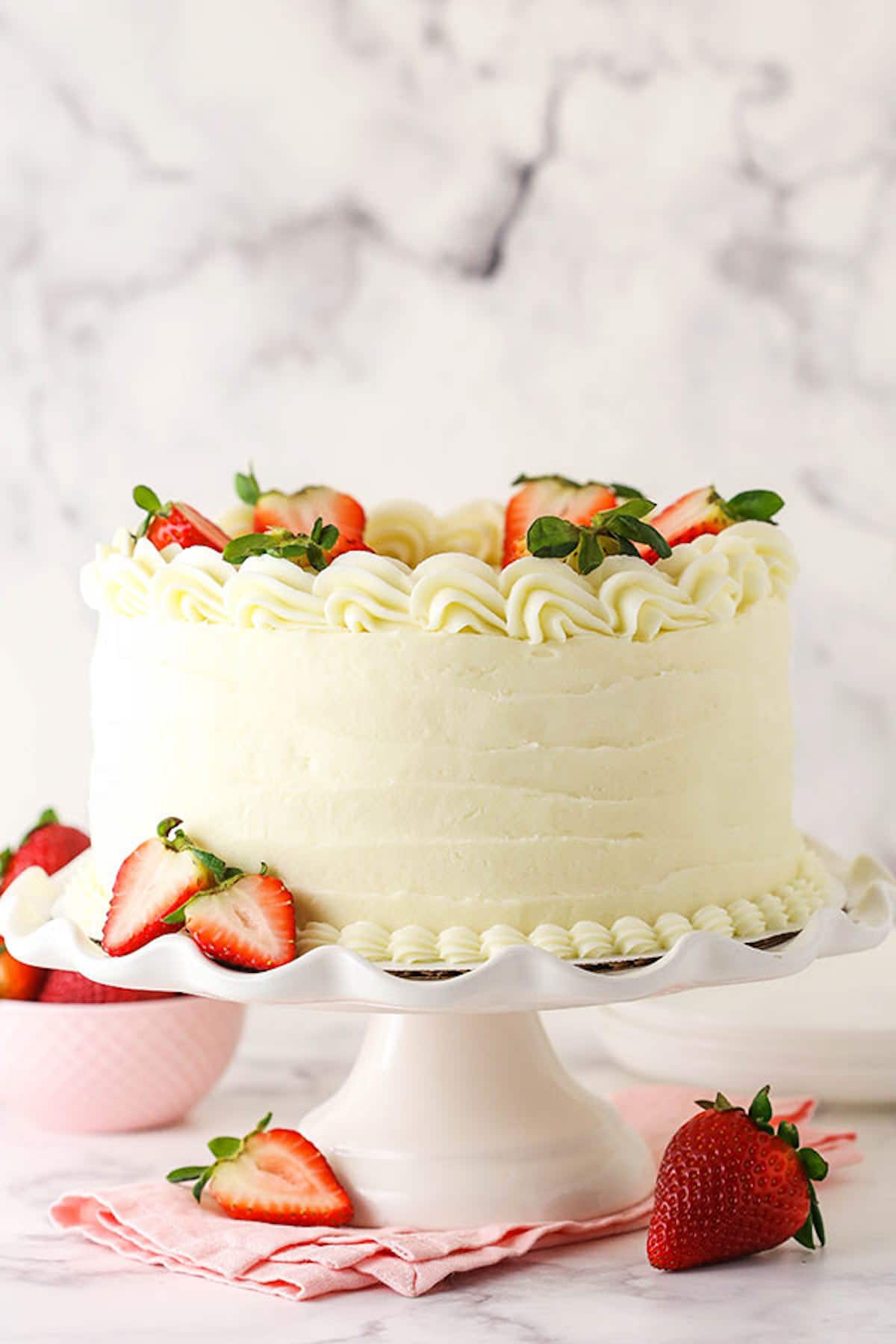 A Cake Stand Holding a Frosted Strawberry Layer Cake