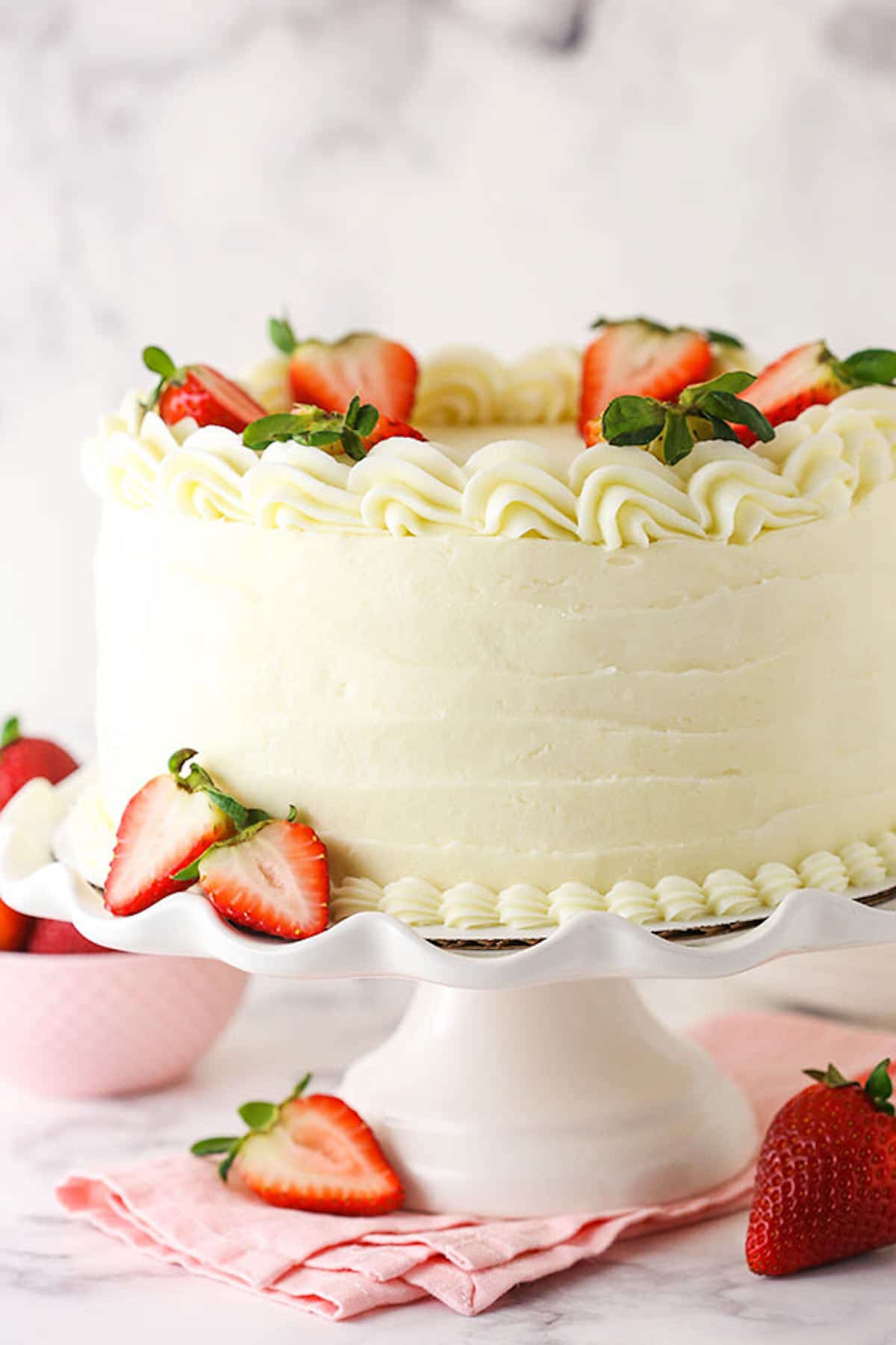 A Strawberry Cake with Cream Cheese Frosting on a White Cake Stand