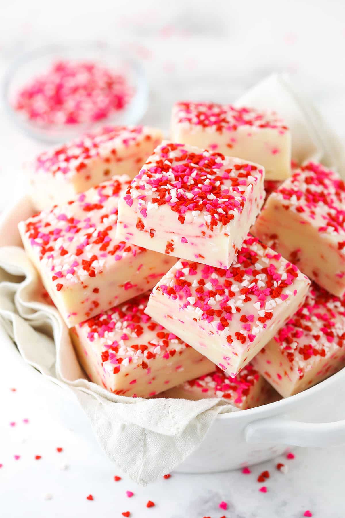 Valentine's Day Fudge squares with red, white and pink sprinkles on top in a bowl. 