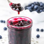 A Spoon Scooping Out Some Homemade Blueberry Sauce From a Jar