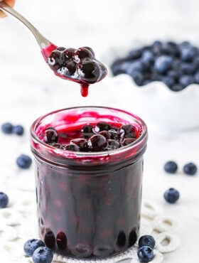 A Spoon Scooping Out Some Homemade Blueberry Sauce From a Jar