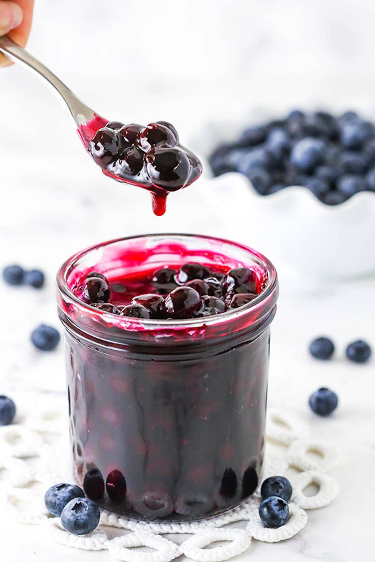 A Spoon Scooping Out Some Homemade Blueberry Sauce From a Jar