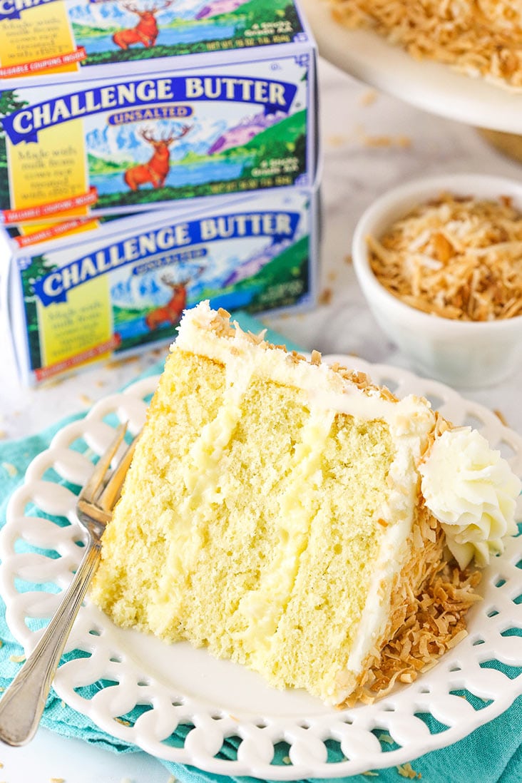 cake slice on a plate with two packages of challenge butter behind it