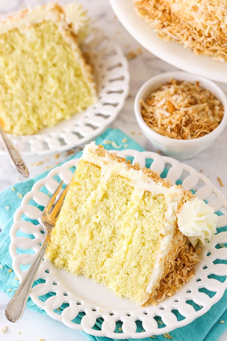 two slices of coconut cake with a bowl of toasted coconut