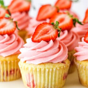 strawberry cupcake on a cake stand with other cupcakes around
