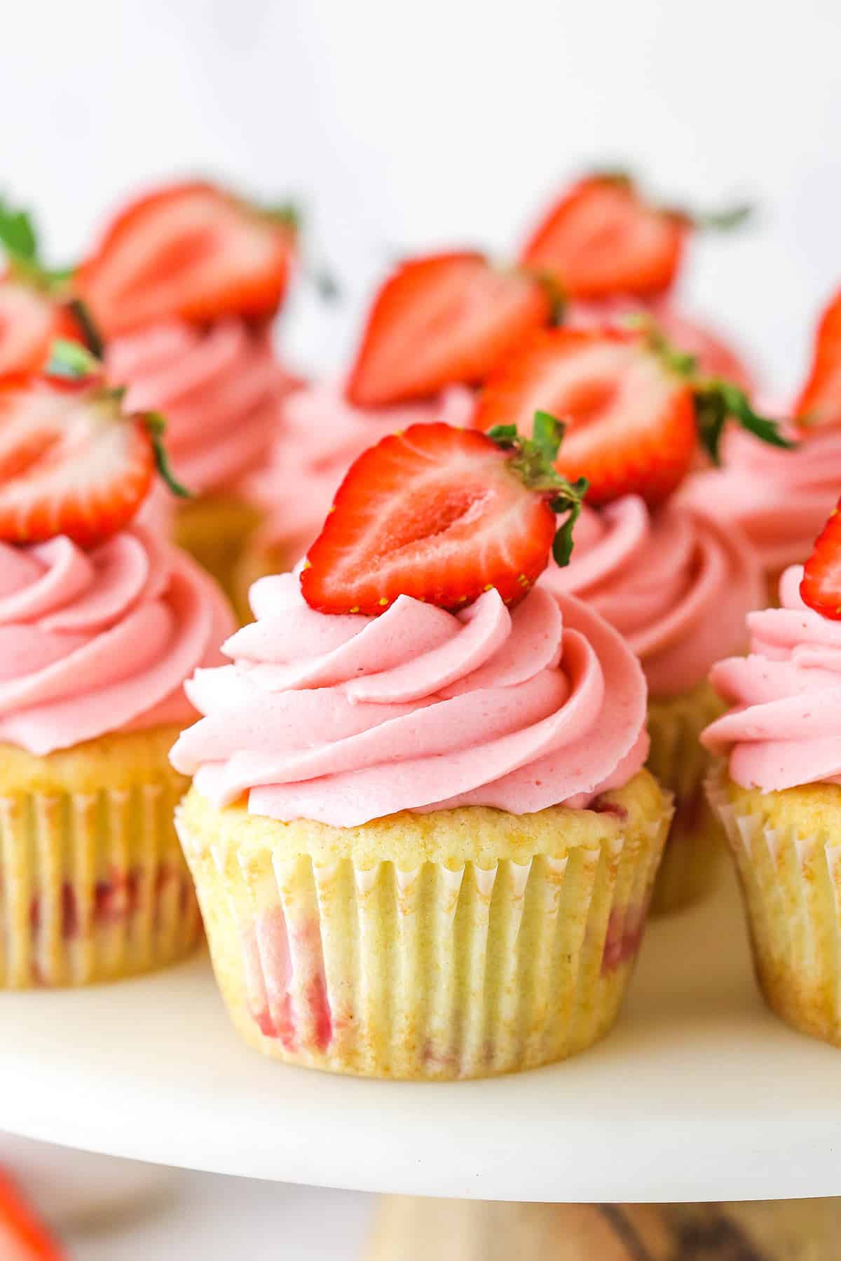 close up of strawberry cupcakes on marble cake stand
