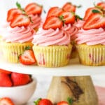 fresh strawberry cupcakes on marble and wood cake stand with strawberries around base