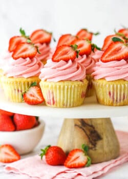 fresh strawberry cupcakes on marble and wood cake stand with strawberries around base