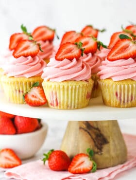 fresh strawberry cupcakes on marble and wood cake stand with strawberries around base