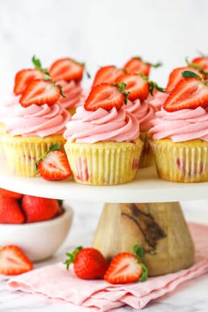 fresh strawberry cupcakes on marble and wood cake stand with strawberries around base