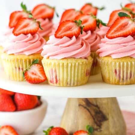 fresh strawberry cupcakes on marble and wood cake stand with strawberries around base