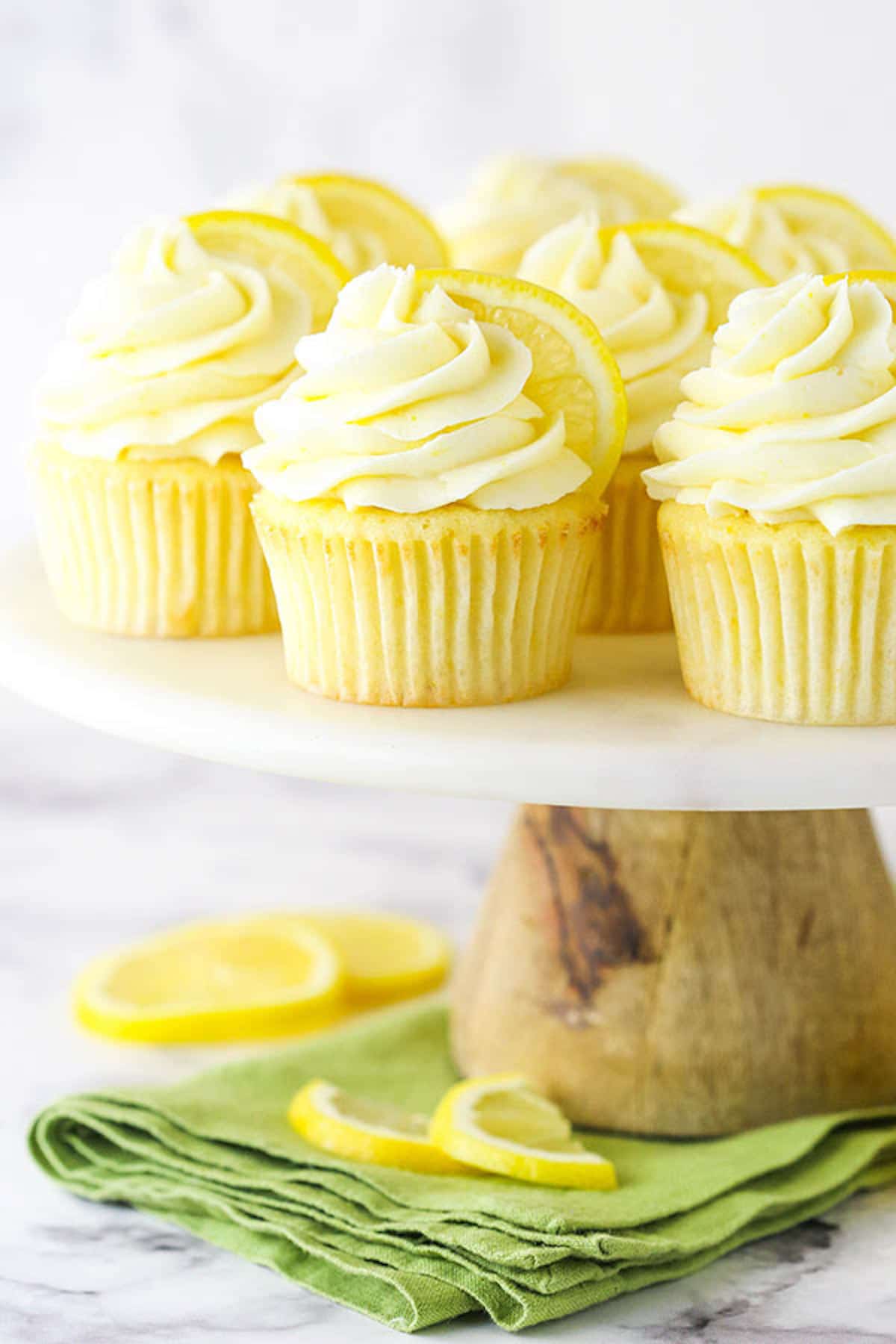 Eight Cupcakes on a White Cake Stand with a Wooden Base