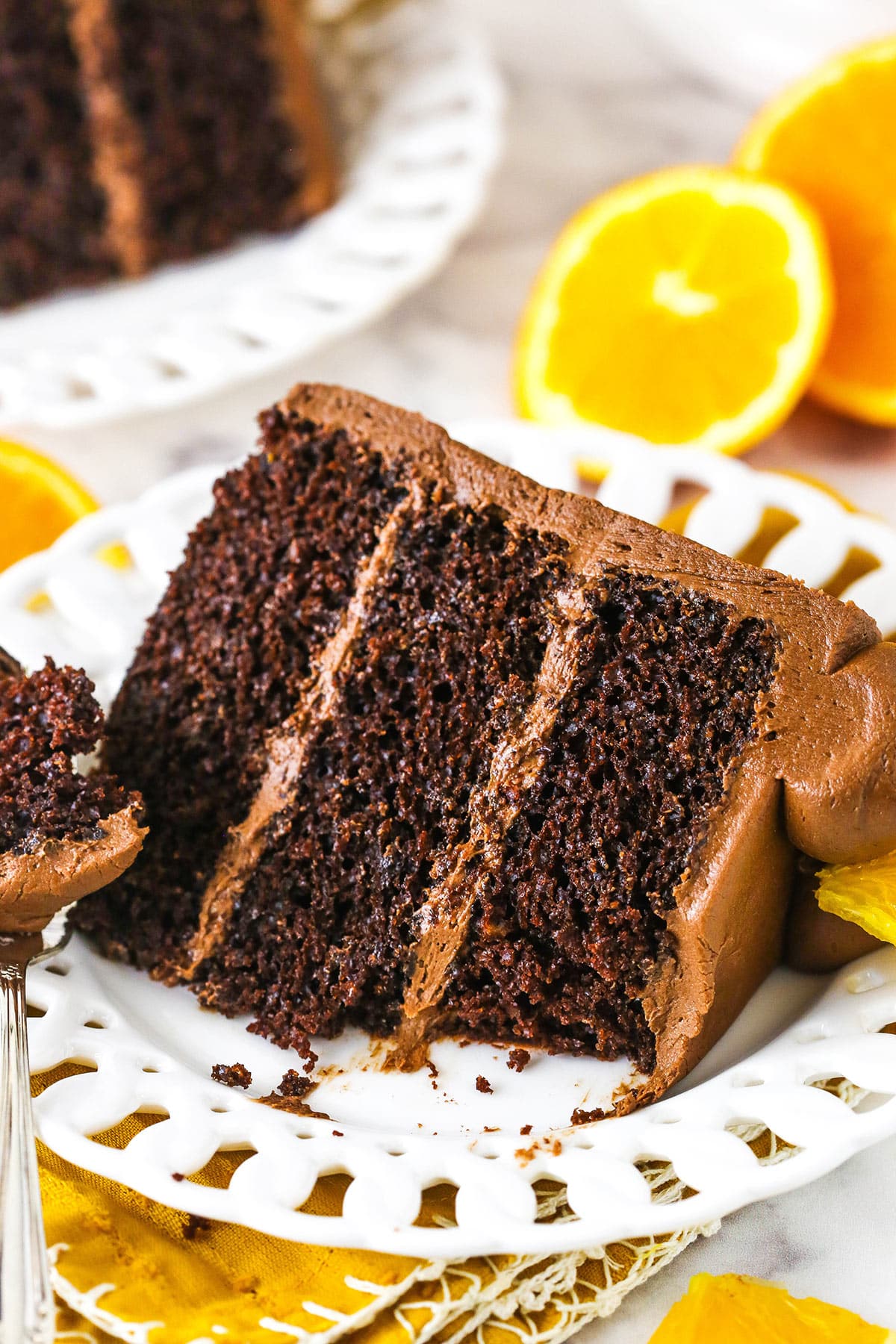 slice of orange chocolate cake on white plate with bite on fork