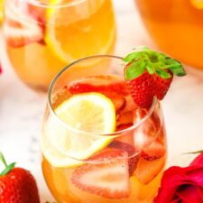 A glass of Rosewater Rosé Sangria garnished with a fresh strawberry